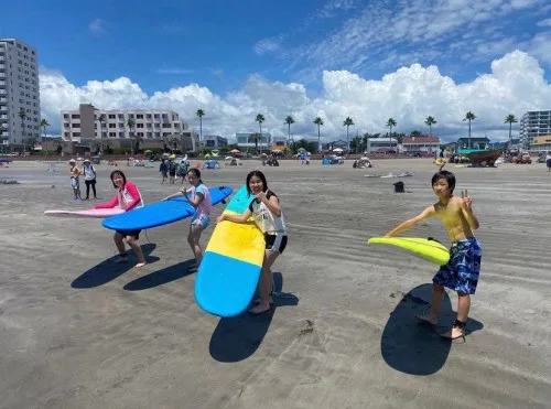 海岸で柔らかいサーフボードを持つ参加者