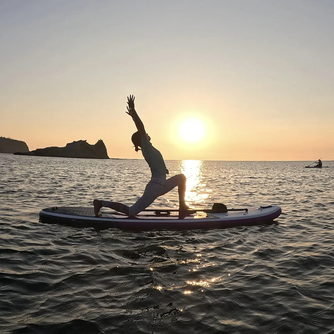 夕日の海でSUPボードの上でヨガをする参加者